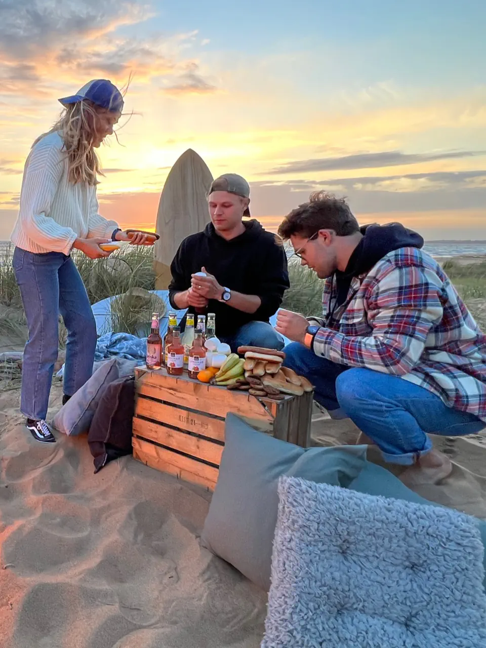 Friends gathered around a bonfire on the beach at sunset